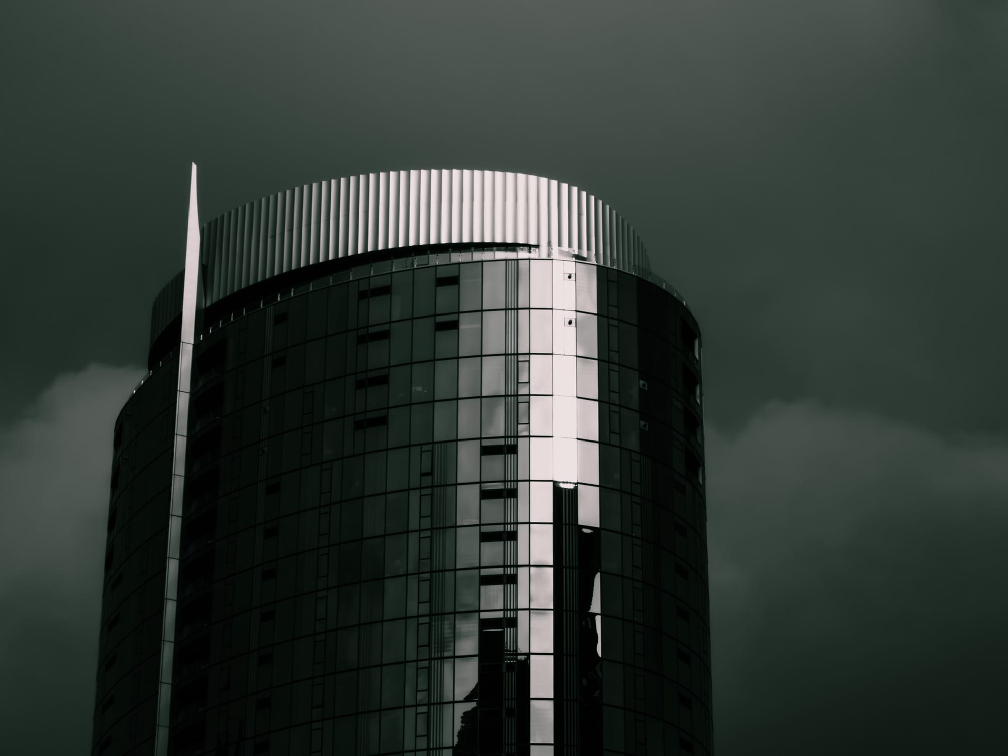 Dark glass tower against moody sky