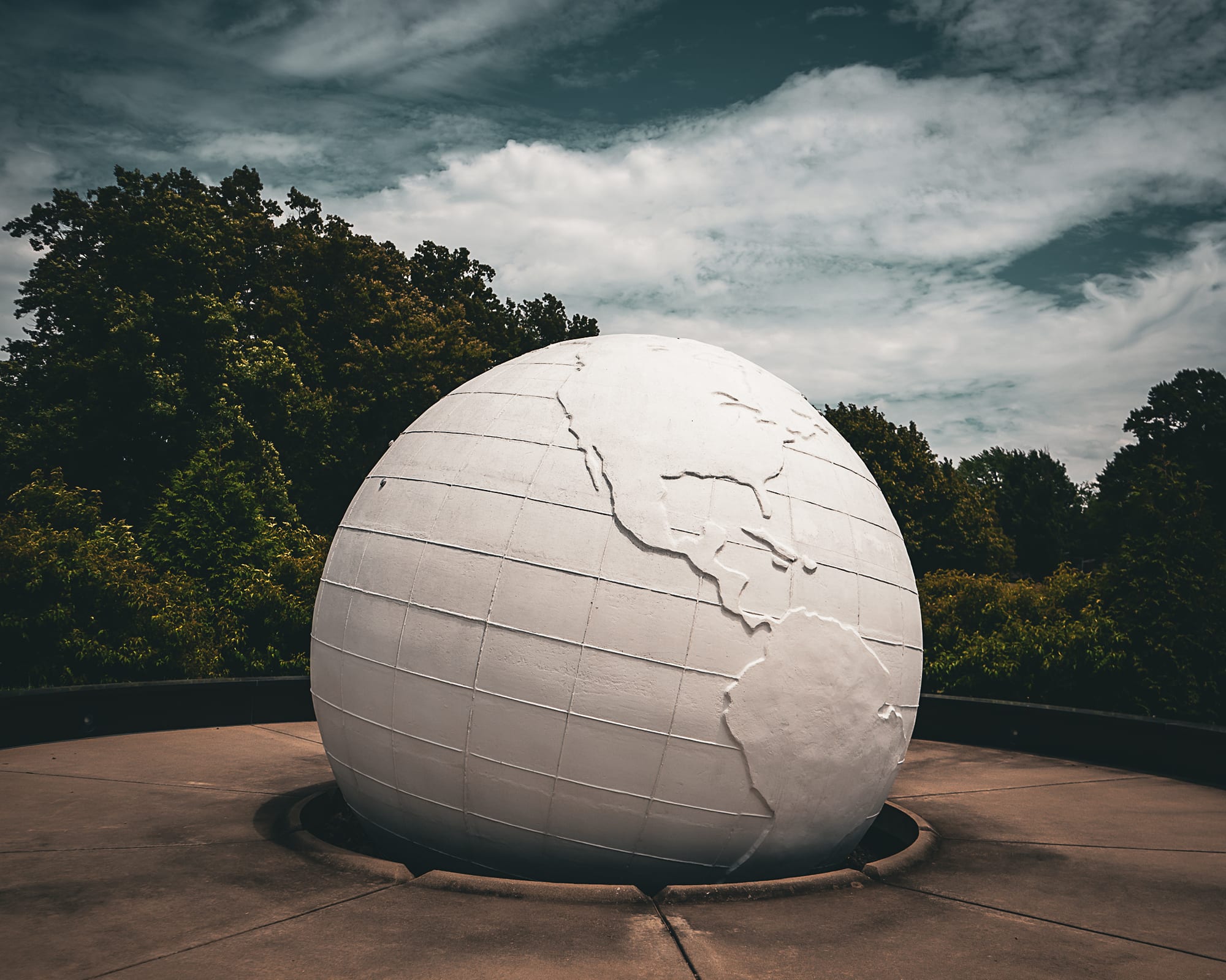White globe sculpture under dramatic sky
