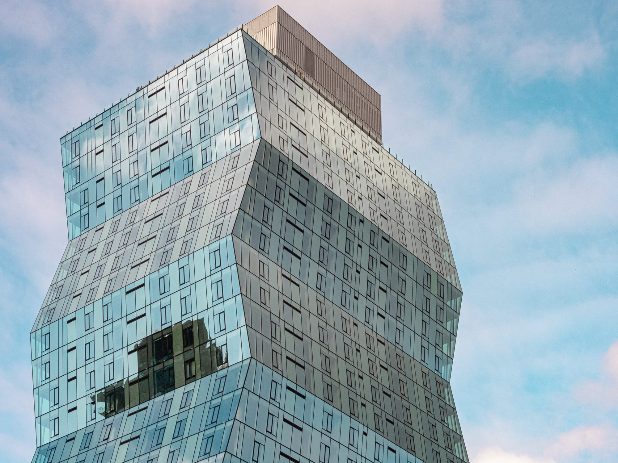 Twisted glass skyscraper against blue sky